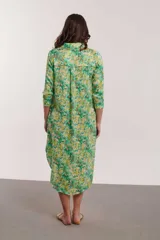 Vestido camisero midi con estampado floral en tonos naranja, rosa y fucsia. Tiene cuello camisero, mangas 3/4 y aberturas laterales.