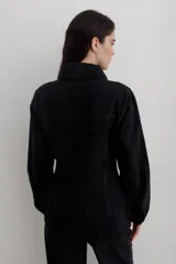 Chaqueta de denim negro, de corte entallado en la cintura, con cuello clásico, cierre frontal de botones metálicos y bolsillos con solapa en el pecho.