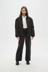 Campera puffer negra con cuello alto, cierre frontal oculto y puños tejidos acanalados. Diseño acolchado con bolsillos laterales.