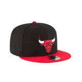 Gorro snapback New Era 9FIFTY de los Chicago Bulls, con corona bicolor negra y roja, visera plana y logo de los Bulls bordado al frente.