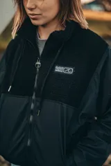 Campera negra con paneles de tela lisa y de corderito, cierre frontal y cuello alto.