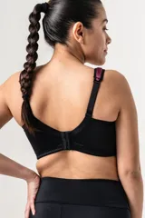 Bralette deportivo reductor negro con breteles anchos magenta regulables y escote alto. Confeccionado en jersey y tela de faja de alta contención.
