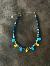 Collar corto con diseño multicolor compuesto por cuentas de cristal checo, piedras naturales y piezas de acrílico en tonos azul, celeste y amarillo, con cierre de cadena de acero quirúrgico.