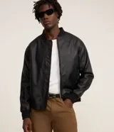 Campera estilo bomber de poliuretano (PU) símil cuero en color negro, con cuello, puños y dobladillo acanalados, y cierre frontal de cremallera.