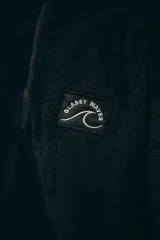 Buzo negro de polar con cierre parcial y logo de la marca bordado en el pecho.