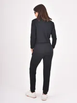 Monoprenda de estilo deportivo color negro, con cierre frontal parcial, mangas largas y cintura elástica con cordón ajustable. Presenta un diseño de pantalón tipo jogger con puños en los tobillos.