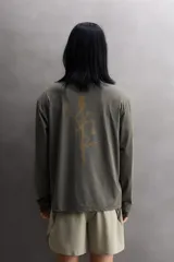 Camiseta de entrenamiento regular fit color gris oscuro, confeccionada en tejido técnico ligero y elástico con estructura. Cuenta con cuello redondo, manga larga y logo estampado en el bajo.