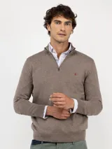 Sweater de punto liso color marrón topo, de corte regular fit, con cuello alto y cierre frontal parcial de cremallera. Cuenta con mangas largas terminadas en puños acanalados y el logo de la marca bordado en el pecho.