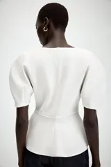 Camiseta negra de cuello redondo con escote en pico, manga corta abullonada y bajo con diseño peplum.