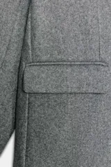 Blazer de corte recto y diseño minimalista, confeccionado en tejido de paño suave color beige. Presenta cuello con solapas clásicas, cierre frontal con un solo botón y dos bolsillos delanteros con solapa.