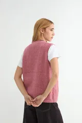 Chaleco de tejido de punto en color beige, con escote en V, cierre frontal con botones oscuros y dos bolsillos delanteros aplicados.
