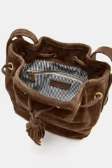 Bolso tipo bandolera de formato mini, confeccionado en piel de ante color marrón. Presenta un diseño de saco con cierre mediante cordón fruncido y detalle de borlas. Incluye una correa larga ajustable y herrajes metálicos dorados.