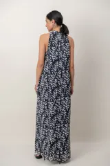 Vestido largo de gasa con estampa en blanco y negro, de líneas simples y escote halter. Cuenta con una sobrecapa cruzada en el frente.