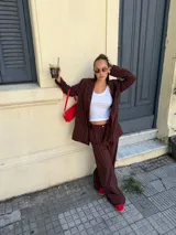 Conjunto de dos piezas compuesto por un blazer y un pantalón de corte sastrero, confeccionados en tela de algodón con estampado de rayas verticales blancas sobre fondo gris. El blazer presenta solapas clásicas y cierre frontal, mientras que el pantalón es de tiro medio y pierna recta.