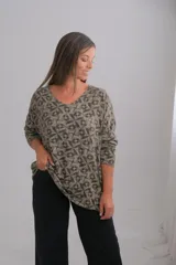 Sweter de punto con escote en V, manga larga y corte amplio. Presenta un estampado geométrico de mosaicos en tonos verdes y oscuros.