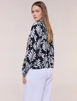 Camperita de lino liviana, marca Dash, con estampado botánico de hojas en tonos azules, verdes y tostados sobre base blanca. Presenta cierre frontal con botones, cuello clásico y bolsillos aplicados en el pecho.