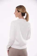 Suéter tejido color blanco con cuello alto y diseño de trenzas.