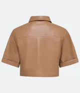 Camisa de manga corta confeccionada en cuero sintético color tostado, con cuello camisero, cierre frontal con botones en forma de corazón y dos bolsillos con solapa en el pecho.