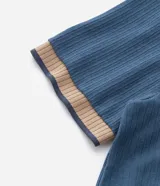 Remera de manga corta, color azul, con textura acanalada vertical. Presenta cuello redondo y puños contrastantes en color beige.