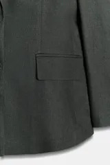 Blazer entallada gris confeccionada en mezcla de lino, con cuello solapa, manga larga con hombreras, falsos bolsillos con solapa en el delantero y cierre frontal con botones.