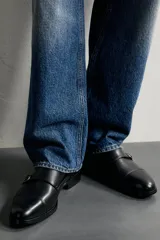 Zapato de vestir tipo monk de color negro, con detalle de doble hebilla metálica plateada en el empeine, puntera redondeada y suela con ligero tacón.