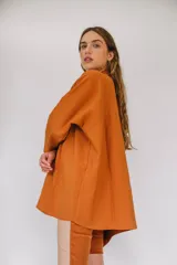 Camisa de sarga color mostaza, de diseño irregular con los costados más largos, mangas largas y corte amplio.