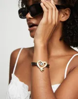 Pulsera de cuero marrón con dije de corazón dorado con cristal negro.