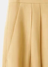 Pantalón recto de tiro medio color beige, confeccionado en mezcla de lino y viscosa. Cuenta con detalle de pinzas, bolsillos laterales y cierre frontal oculto con cremallera, botón y ganchos con tapeta.