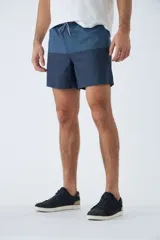 Short de baño con diseño de bloques de color en dos tonos de azul, cintura elástica con cordón ajustable, bolsillos laterales y bolsillo trasero. Incluye suspensor interno y logo bordado.