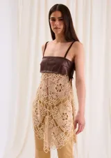 Top largo con cuerpo de cuero marrón chocolate y diseño inferior de crochet en tono beige, con tirantes finos y flecos laterales.