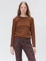 Remera de manga larga con cuello a la base, confeccionada en tejido de punto acanalado color beige. Presenta un logo bordado en el centro del pecho.