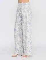 Pantalón palazzo de tiro alto con estampa floral azul sobre base beige, corte de pierna ancha, cintura elastizada con cordón de ajuste y bolsillos laterales.