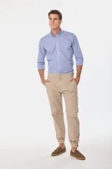 Pantalón de vestir color beige, de corte recto, con bolsillos laterales y traseros. Se ajusta a la cintura con cinturón de cuero marrón. Tiene puños elásticos en los tobillos.