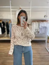 Sweater calado color crudo, de manga larga y cuello redondo.