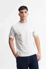 Remera de manga corta color beige claro, con escote redondo y fit regular. Presenta un estampado frontal con letras góticas en blanco.