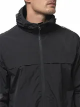 Campera rompevientos de nylon color gris, con capucha ajustable, cierre frontal completo, bolsillos laterales con cierre, puños elásticos y ruedo ajustable.