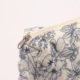 Necesér acolchado con estampado floral en azul sobre fondo blanco, cierre de cremallera y etiqueta con texto.