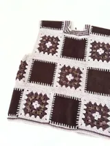 Chaleco sin mangas, confeccionado con cuadrados de cuero negro perforado combinados con cuadrados de crochet en hilo de algodón negro y blanco, con detalles centrales en rojo.