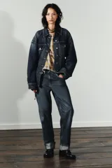 Pantalón de jean azul oscuro de corte recto, tiro medio, con bolsillos delanteros y traseros, trabillas para cinturón y ruedo doblado. Cierre frontal con cremallera y botón metálico.