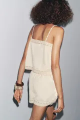 Bermuda color crudo confeccionada en algodón y lino, con tiro medio, cintura elástica ajustable con cordones y bordado floral a contraste en los laterales.