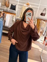 Blusa de color bordó con cuello drapeado y detalle de cinta tipo choker integrada. Presenta mangas largas con puños abotonados y un corte holgado y fluido.