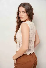 Chaleco de crochet color beige, sin mangas, con escote en V y botones frontales. Cuenta con bordados florales en tono marrón, celeste y ocre en la parte delantera y diseño con ondas en el ruedo.
