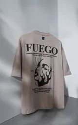 Remera de manga corta y cuello redondo con calce oversize, color beige con estampa gráfica en negro que incluye texto y un rostro femenino estilizado con llamas.