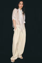 Camisa blanca de tejido semitransparente ZARA Woman Collection, con cuello redondo, manga corta y detalle de pañuelo integrado en el mismo tejido al cuello. Cierre frontal con botones.