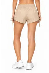 Short de poliamida color beige, holgado, de tiro medio con cintura elástica y detalles de frunces con cordones ajustables en los laterales.