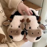 Pantuflas de peluche con diseño de vaca, confeccionadas en piel sintética suave. Cuentan con suela de goma antideslizante y diseño abierto en el talón.