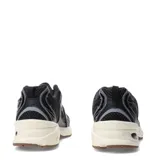 Championes New Balance modelo 530, con diseño retro-deportivo. Presentan una capellada de malla transpirable en color negro con refuerzos sintéticos en tonos grises y negros. Incluyen entresuela con tecnología ABZORB en color crema y suela de goma en tono marrón.