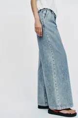 Jeans de tiro medio con pernera ancha, diseño wide leg y pinzas delanteras. Cuenta con bolsillos frontales, bolsillos traseros de plastrón y cierre frontal con cremallera y botón.