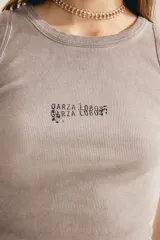Musculosa de morley color gris con textura acanalada, cuello redondo, sin mangas y pequeño estampado tipográfico en el pecho.
