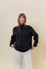 Sweater tejido de punto color blanco, con cuello alto y diseño en relieve tipo chevron en la parte frontal. Presenta un calce holgado con terminaciones acanaladas en puños y ruedo.
